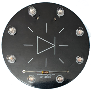 A black circular circuit board with eight LEDs outlining the edge and a resistor along the bottom. Just beneath the resistor is the text "www.mrblinkbling.com GET NOTICED!"